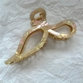 Close-up of cream acetate bow hair claw with elegant iridescent finish and gold hardware - Pink & White