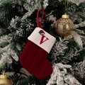 Red knit Christmas stocking with embroidered letter V on a snowy pine branch - Style V