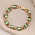 Detail of luxury gold chain bracelet with emerald green stones on beige silk texture - Gold Eight Rectangle Green Gems Bracelet (WG-0420)