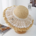 Détail d'un chapeau en paille avec broderie de dentelle blanche et élégant nœud noir - Taille unique / Kaki