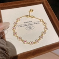 Macro detail of 18K gold-plated circular bracelet with red and white zircons. - Gold