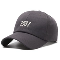 Dark grey cotton baseball cap featuring white 1987 number embroidery and curved brim - Gray