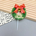 Close-up of Christmas cake topper with green tinsel wreath, red bow, and gold bells - Wreath-1002