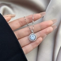 Collier avec pendentif en zircon argenté sur soie champagne tenu dans une main - 0627-Argent Rond Pierre Blanche