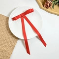 Detail of red ribbon bow hair clip with long streamers on a decorative white plate - Red