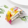 Macro shot of U-shaped acetate hair claw with tortoiseshell pattern and silver metal spring - Colorful
