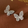 Nahaufnahme silberner Schmetterlings-Ohrstecker mit Zirkonia-Steinen auf einem Buch - Silberner Schmetterling (Silbernadel)