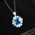 Makroansicht einer blauen rechteckigen Halskette mit Zirkonia-Halo auf schwarzem Samt - Blauer Zirkonia-Anhänger (Ohne Kette)