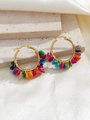 Detail of colorful stone wrap earrings on beige travertine with cream silk background - Colorful