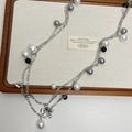 Detail of multi-layer gray pearl necklace with floral and heart pendants on tray - Black and White Beaded Necklace
