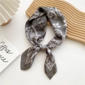 Dark grey silk square scarf with white paisley pattern tied as a bow on a white desk - Floral Grey