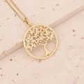 Macro shot of gold Tree of Life pendant with multicolor cubic zirconia on stone texture - Round Tree of Life