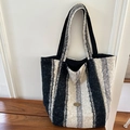 Macro detail of plush faux fur texture and 'Handmade' metal logo on striped tote bag - Black and White Stripe Plush Style