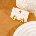 Golden oval stainless steel earrings featuring vertical ribbed texture on white stone - Letter O
