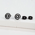 Minimalist black stainless steel ear studs featuring a modern at symbol geometric design - @ Symbol Black