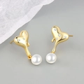 Macro shot of gold heart-shaped stud earrings with zircon inlay and hanging white pearl - Liquid Artificial Pearl Stud Gold
