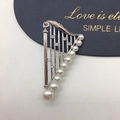 Macro shot of silver harp brooch featuring gradient freshwater pearls and micro-pave crystals - Harp Gradient Silver