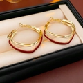 Detailopname van dubbellaagse geometrische oorbellen van goud metaal en rood email op display - Goud-Rood
