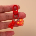 Cute red resin bear and heart keychain charm with matching red metal clasp on hand - Red
