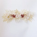 Detail of cream and dusty rose artificial flower row with faux foliage on white background - Champagne