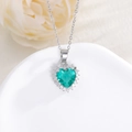 Macro detail of a heart-shaped emerald pendant with a brilliant diamond halo and silver chain - Light Green