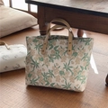 Borsa tote floreale in tela con manici in pelle su pavimento in legno accogliente - Foglie Verdi Fiori Albicocca