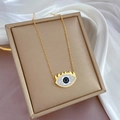 Macro detail of gold eye-shaped pendant with blue center stone on jewelry box - Gold