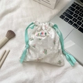 Detail of white velvet drawstring bag with bear and floral prints next to brushes - Off White