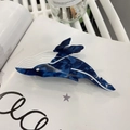 Macro shot of whale-shaped acetate hair claw clip with blue marble texture on a book - Blue Whale
