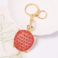 Vista dettagliata del portachiavi a tartaruga con strass rossi e metallo dorato lucido - Stile rosso