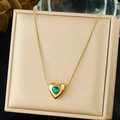 Detalle de un colgante de corazón dorado con gema verde en una cadena de serpiente elegante - Estilo Verde Esmeralda (N3973)