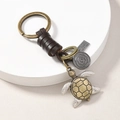 Detailed macro view of retro turtle keychain with leather rope and bronze hardware - Turtle
