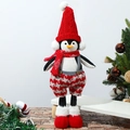Dettaglio di peluche pinguino natalizio con cappello rosso e sciarpa scozzese in posa - Pinguino con gambe telescopiche e cappello rosso
