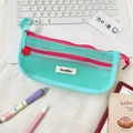 Macro detail of mint green mesh pencil case with pink double zippers on a desk - Green