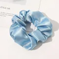 Macro detail of sky blue silk satin scrunchie showing glossy texture and pleats - Sky Blue