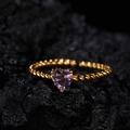 Detailansicht eines herzförmigen lila Edelsteins auf einem gedrehten goldenen Silberring - Natürlicher Amethyst Gold