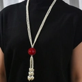 Collana lunga di perle con nappa e perla rossa su sfondo di maglione nero - Stile Sfera Rossa