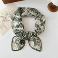 Green and beige floral cotton linen scarf tied in a knot on a white desk with warm decor - Ethnic Green