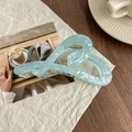 Detail of a large pearlescent heart hair claw clip on a paper and magazine background - Iridescent Blue Green