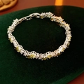 Close-up of silver tennis bracelet with yellow gemstones on dark green velvet - Green