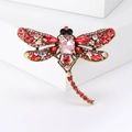 Detail of vintage bronze dragonfly brooch with red and pink crystals on white base - Antique Gold Pink