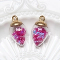 Close-up of heart-shaped glass pendants with pink and blue star sequins on ceramic plate - Water Drop / Rose Red