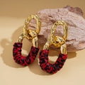 Detalle de pendientes dorados irregulares con anillos de textura tejida en rojo y negro - Poste de pendiente de plata - Rojo