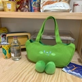 Schattige groene canvas draagtas met cartoon borduursels en pluche pompons op houten tafel - Erwtengroen / Groen