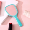 Handheld makeup mirror in mint green with a smooth handle on a soft pink background - Grass Green