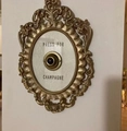 Detail of vintage gold Press For Champagne button with ornate embossed frame on wall - Standard