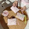 Detailed view of quilted floral coin purses on a sunlit table with natural textures - Patchwork Flower Girl