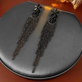 Primer plano de pendientes de flores negras con borlas en un soporte de joyería gris - Color gunmetal