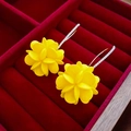 Detail von gelben Blumenblüten-Ohrringen mit funkelnden Kristallhaken auf rotem Samt - Gelber Acryl-Blumen-Ohrhaken