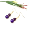 Detailed view of handmade gold wire wrapped earrings with deep purple crystal beads - Gold + Amethyst